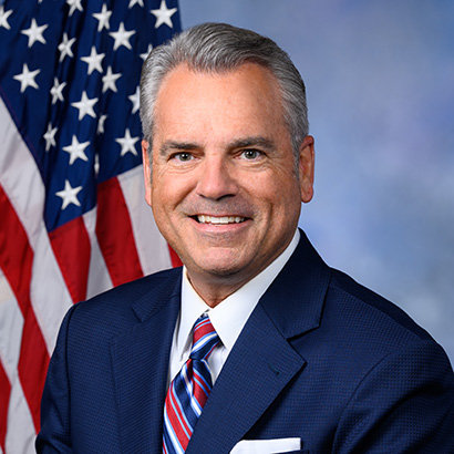 Middle-aged white man with grey hair wearing a dark suit