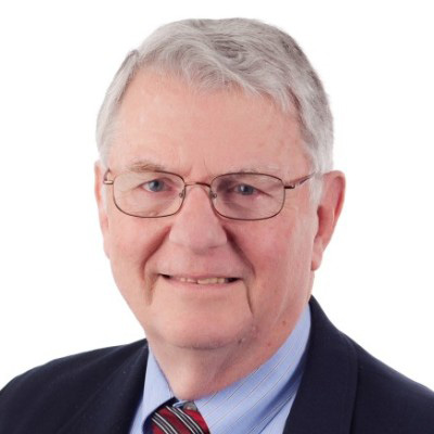 Older white man with white hair wearing glasses and a black suit