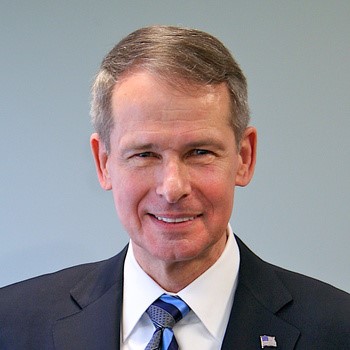 Older white man with light brown hair wearing a dark suit