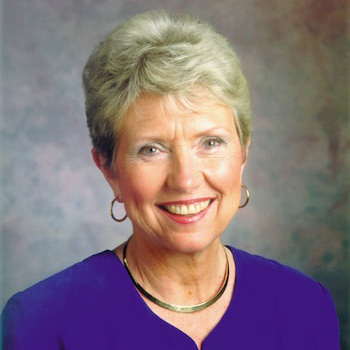 Older white woman with short white hair wearing a blue top
