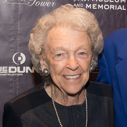 Older white woman with curly white hair wearing a dark top