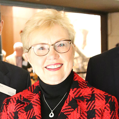 White woman with short blonde hair wearing glasses and a red plaid jacket
