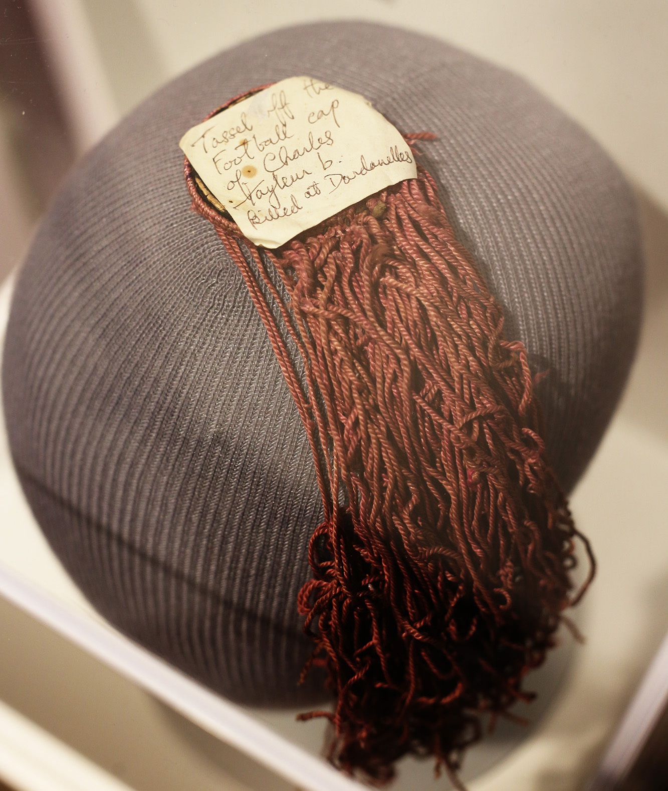 Modern photo of a mannequin head with a dark red-brown tassel stuck to the top