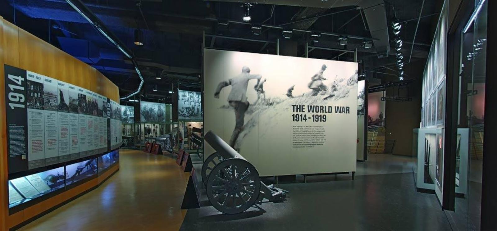 Modern photograph of the Museum main gallery. A trench gun is in the foreground. The timeline display stretches away from the viewer.