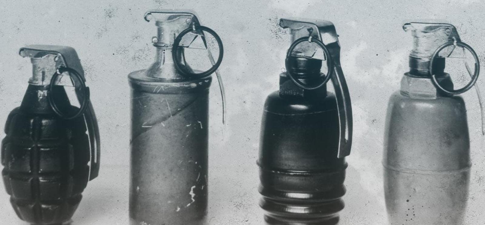 Black and white photograph of four grenades lined up in a row, each of different sizes and shapes.