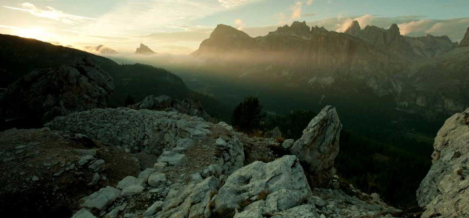Panoramic shot from a mountain ridge at sunrise or sunset, facing another mountain ridge in the distance.