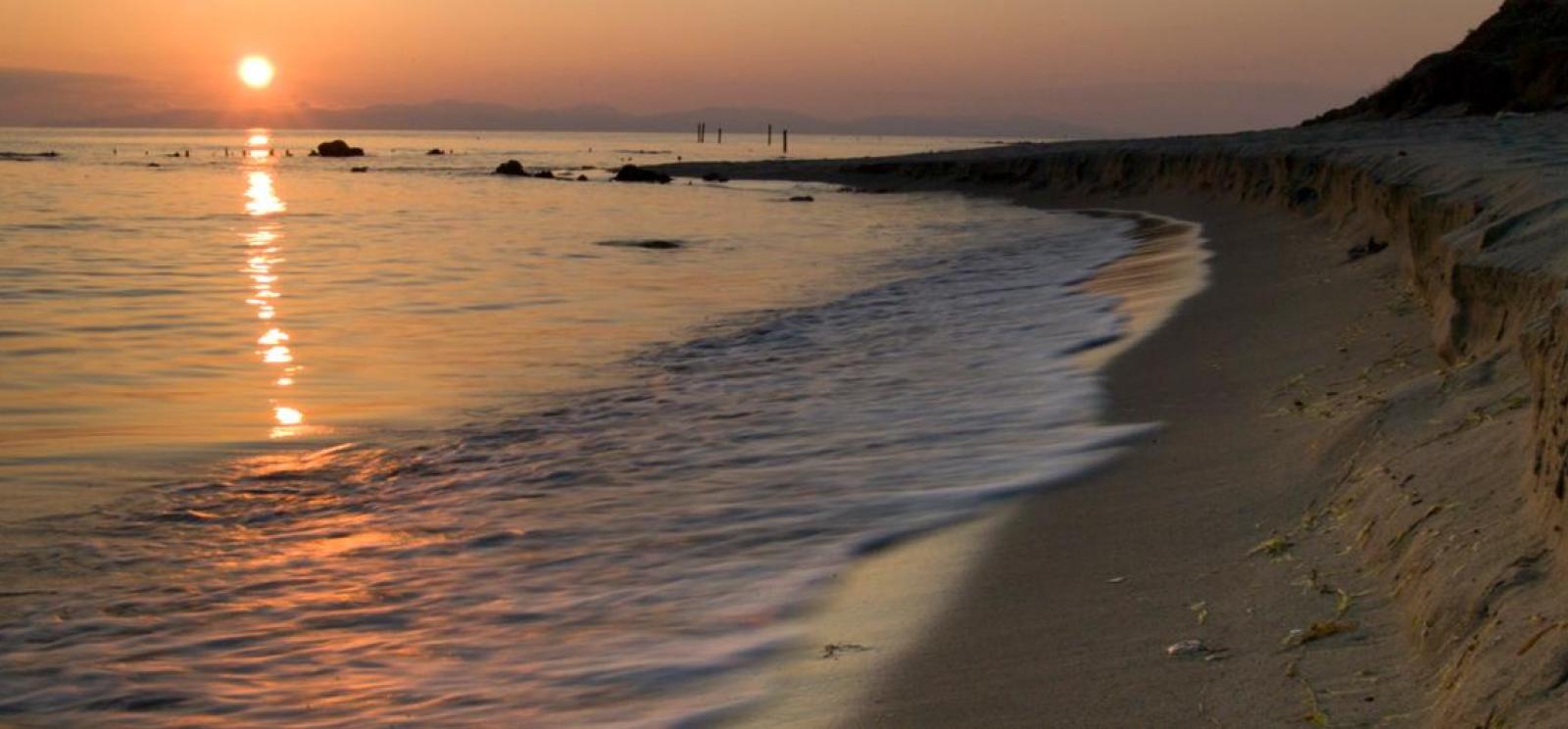Photograph of a beach and shoreline at sunset.