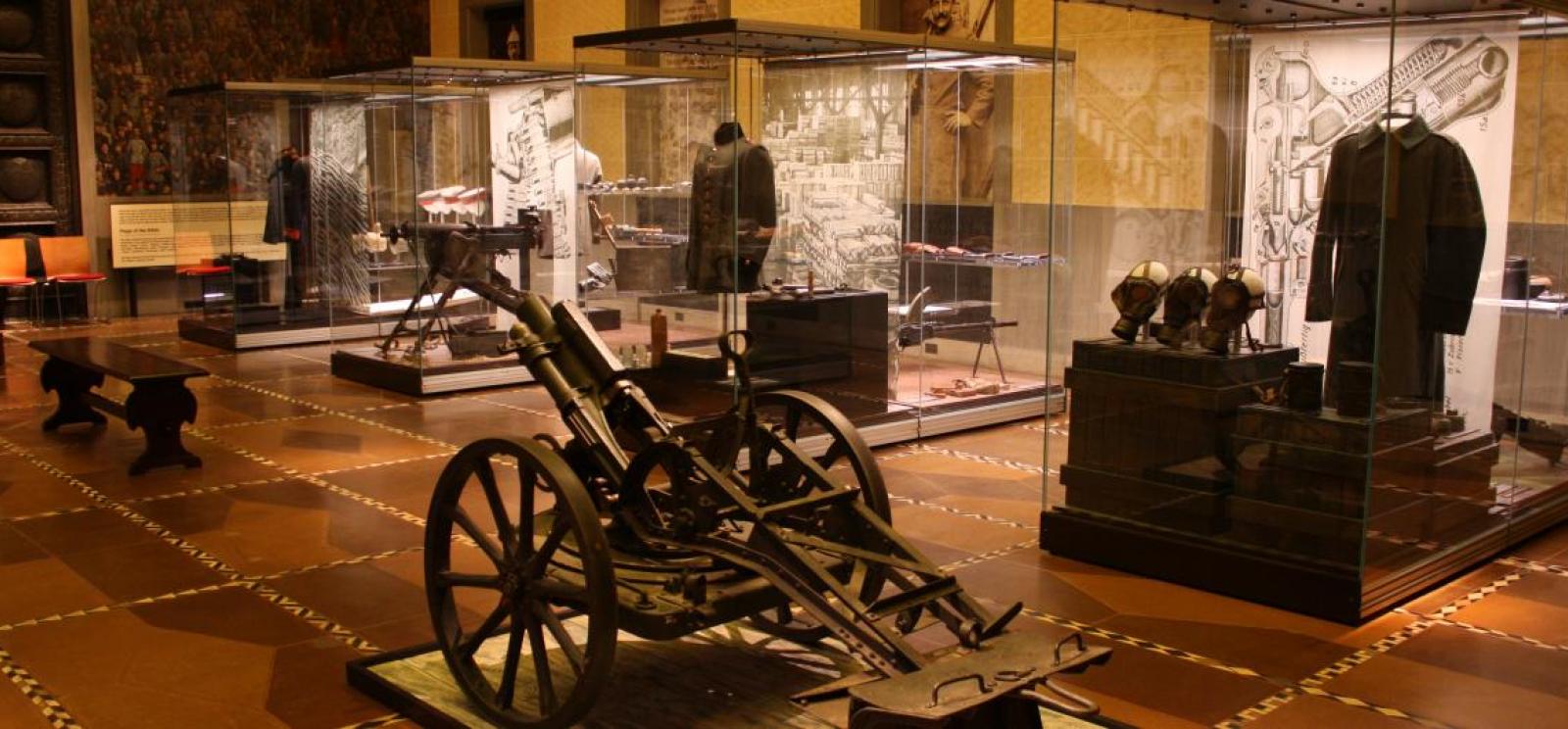 Photograph of a museum exhibition featuring displays of uniforms and artillery.