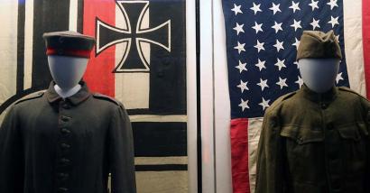 Photograph of two military uniforms under the German and American flags