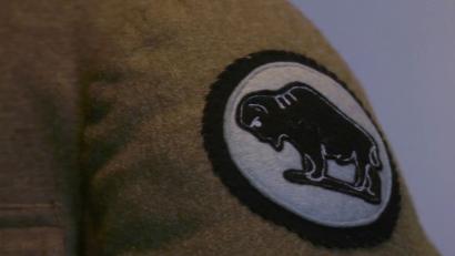 Video still of the arm of a woolen jacket with a patch depicting a silhouette of a bison.