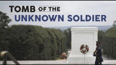 Background image: Modern photograph of a large marble tomb with a wreath placed in front of it and a soldier guarding it. Foreground text: Tomb of the Unknown Soldier.