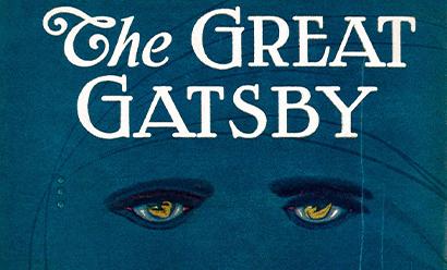 Cropped version of the cover of a novel: "The Great Gatsby" written in white all-caps letters on a deep blue background. Underneath are two painted eyes.
