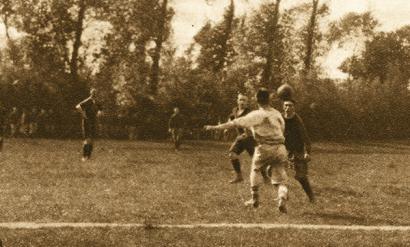 Sepia photo of several WWI soldiers on a field playing football (soccer)