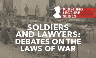 Black and white photo of a court martial trial. There are men in military uniform sitting at a table on a dais. In front of them are a couple rows of tables with more men wearing suits or uniforms. To the side are uniformed men seated in close rows.