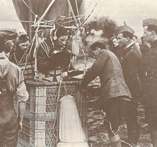 Black and white photograph of a man in a hot air balloon basket on the ground surrounded by a group of soldiers preparing the basket for flight