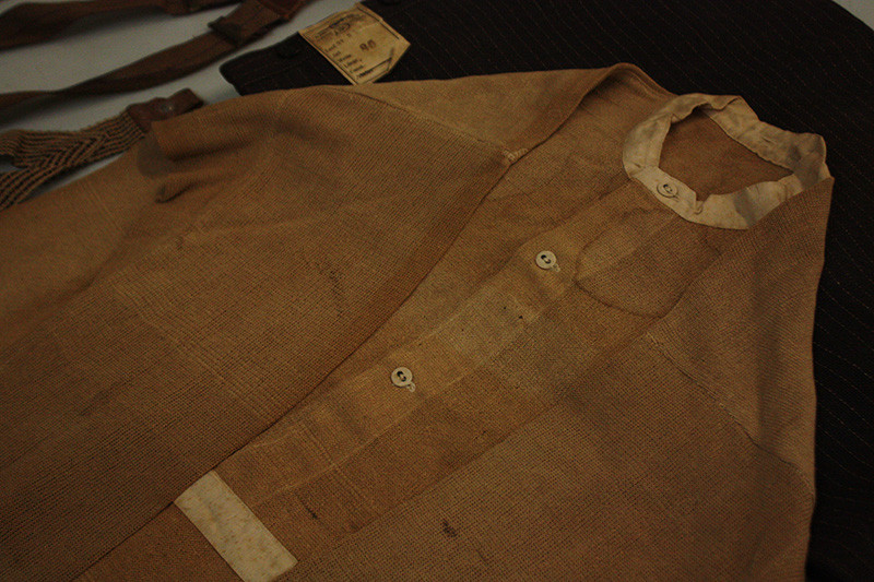 Modern photograph of a brown button-up shirt laid flat on a dark background