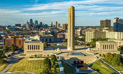 Modern photograph of a soaring aerial view of the Liberty Memorial Tower, Memorial Courtyard, Memory and Exhibit Halls and the Kansas City skyline beyond.