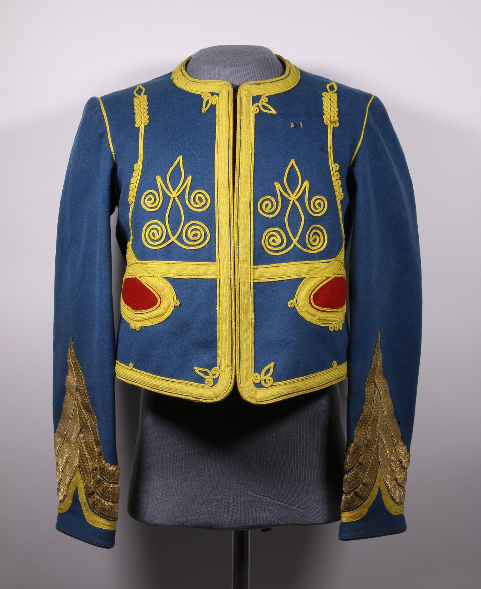 Modern photograph of a bright blue uniform tunic embroidered with bright yellow and red designs
