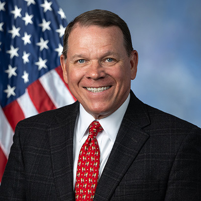 Middle-aged tanned white man wearing a black suit and red tie