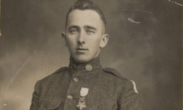 Black and white studio photograph of a man in a uniform with a medal on his chest.