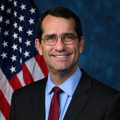 Portrait photo of a middle-aged white man with dark hair wearing glasses
